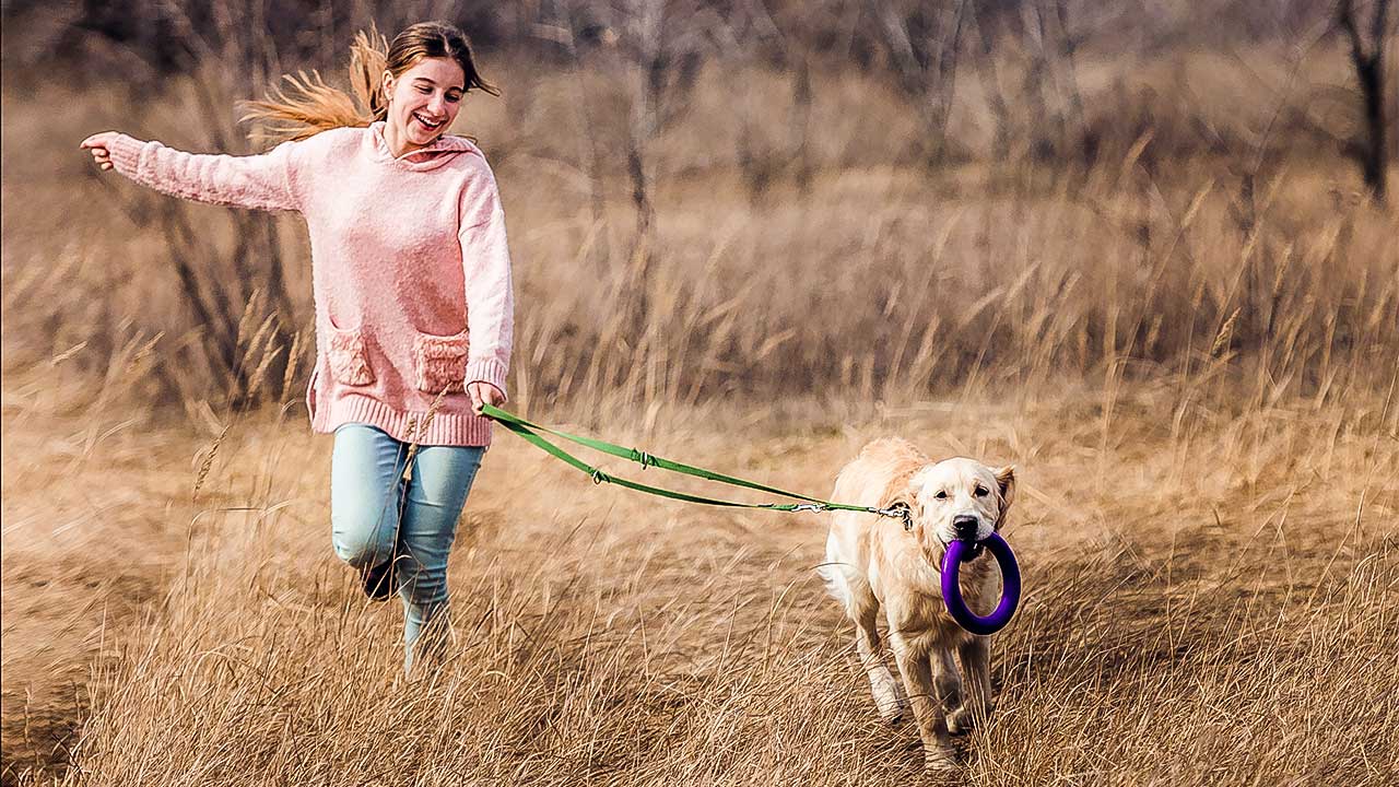 Teenagerin rennt mit Hund über ein Feld