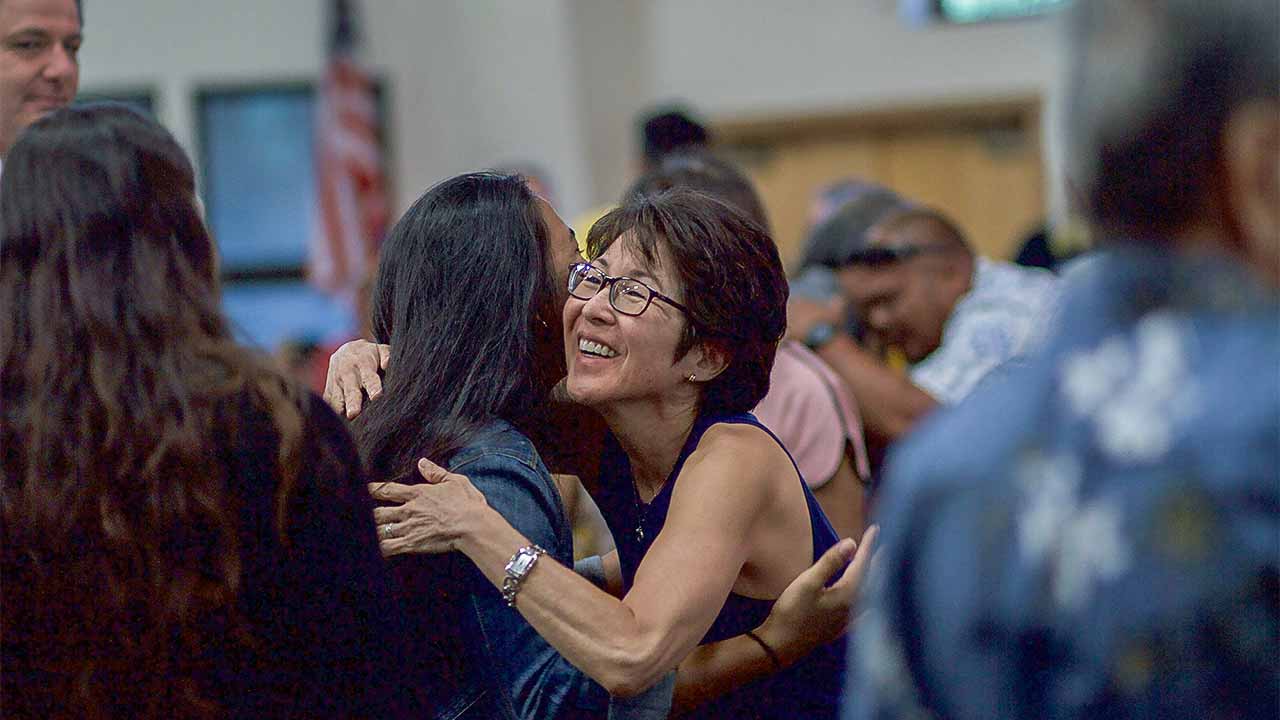 zwei Frauen umarmen sich in einem Gottesdienst in Hawaii