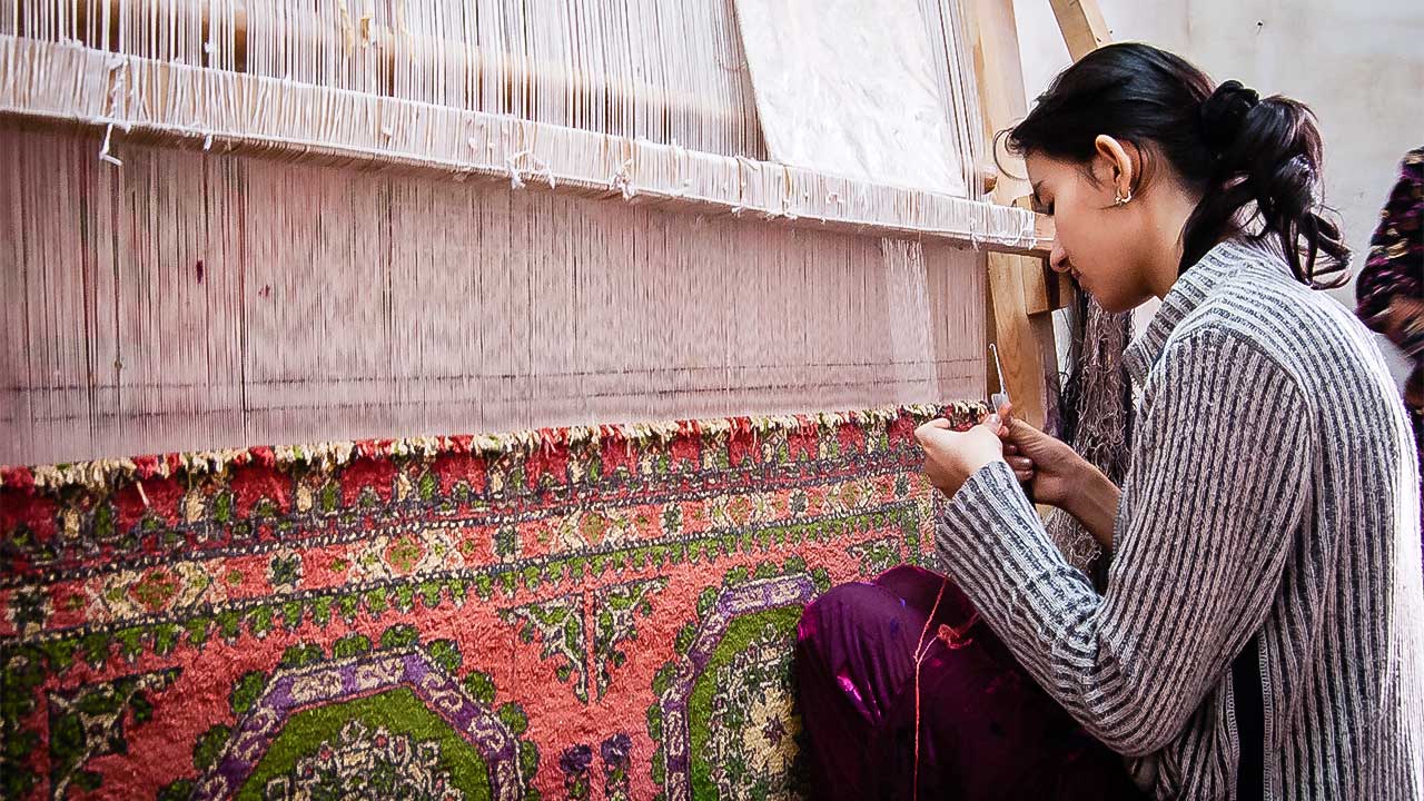 Frau in Bukhara, Usbekistan webt einen Teppich