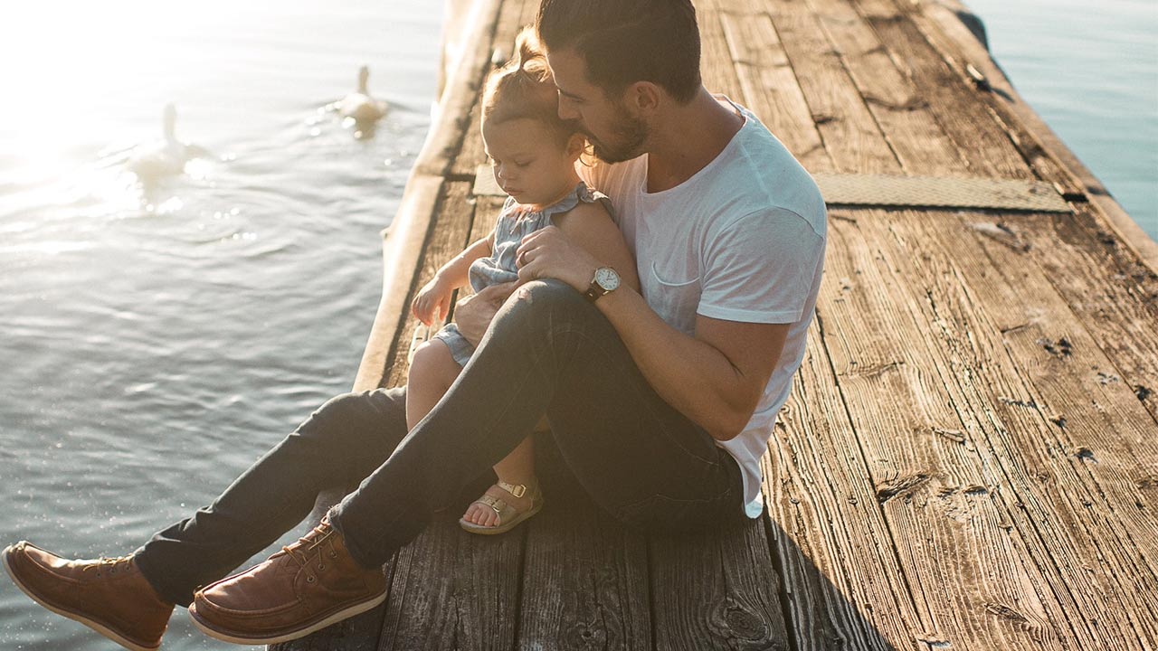 Vater und Tochter sitzen auf einem Steg | (c) unsplash