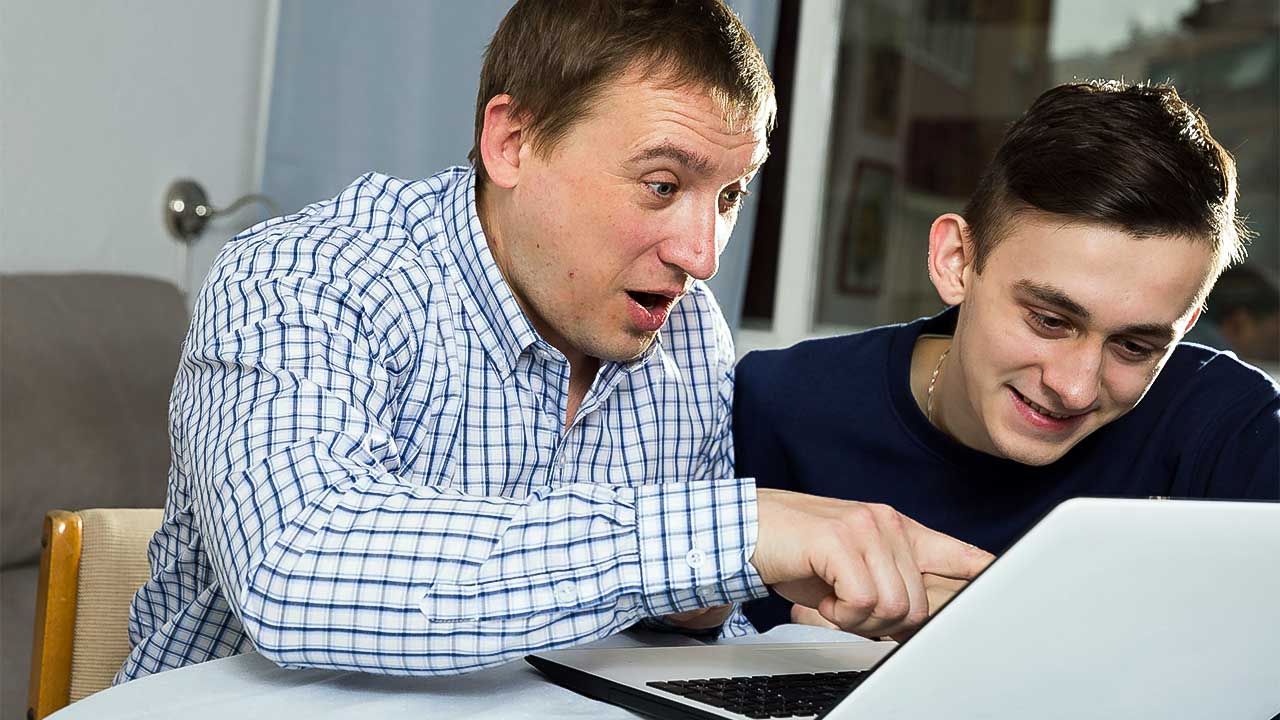Vater und Sohn entdecken zusammen auf einem Laptop