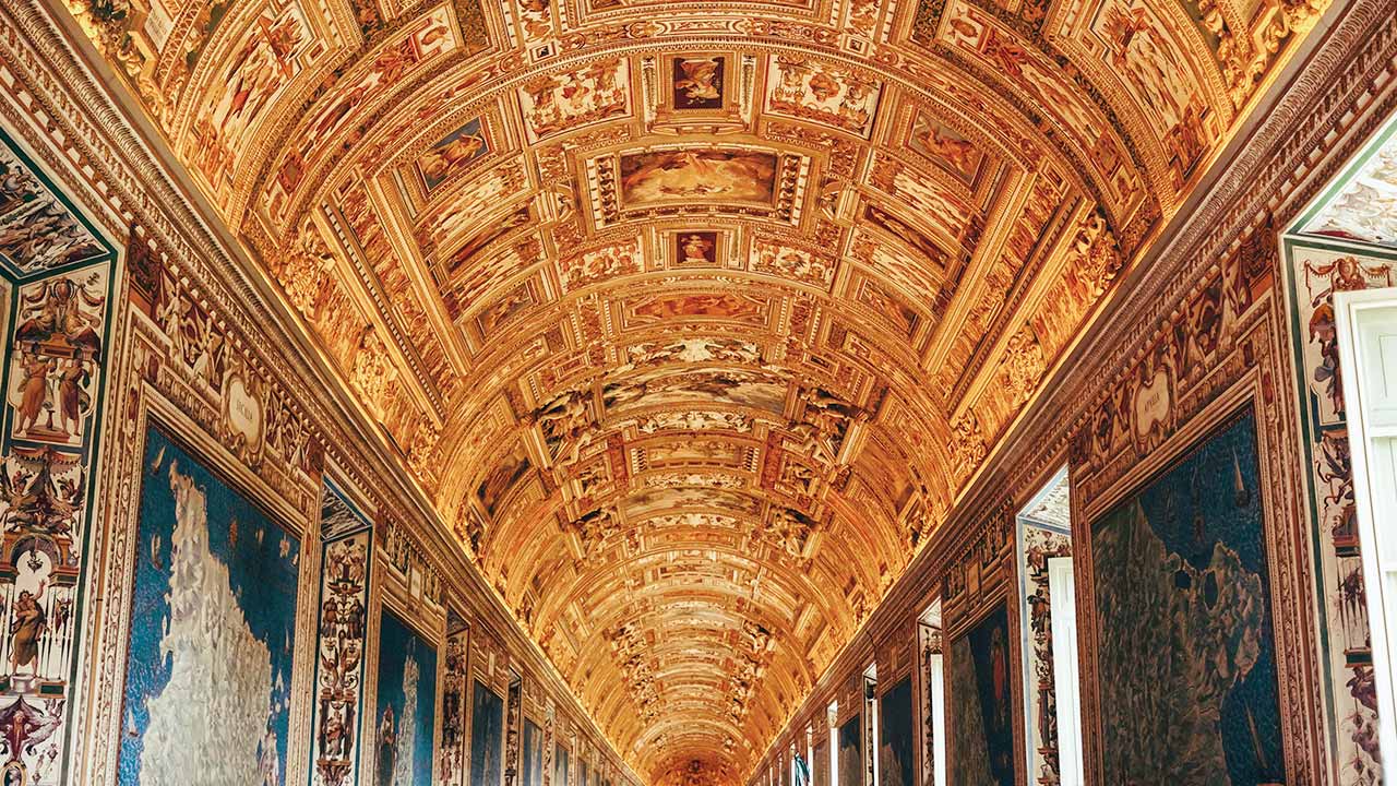 Blick in einen Gang im Vatikanischen Museum im Vatikan. An der Decken sind mehrere Gemälde.