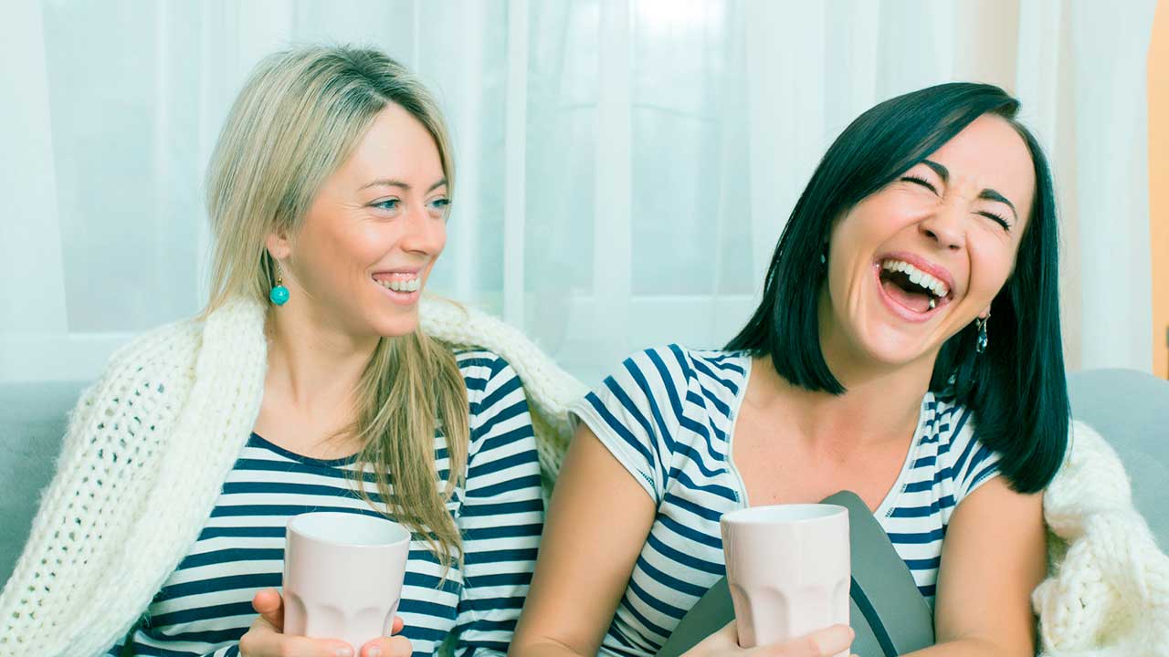 Zwei junge Frauen sitzen auf dem Sofa und haben eine gute Laune