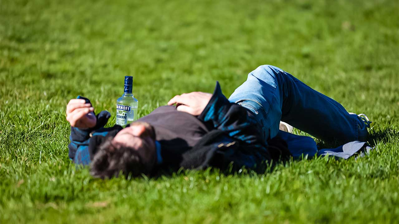 Mann liegt betrunken auf einer Wiese