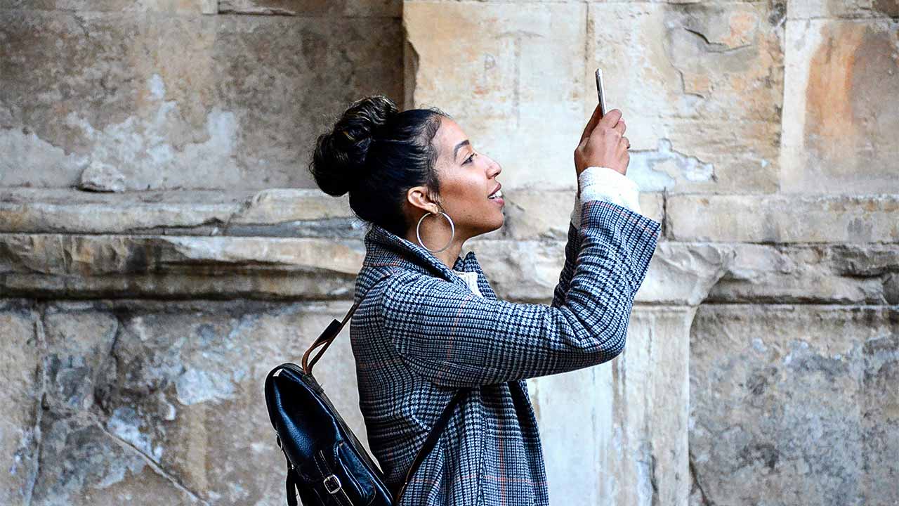 junge Frau hält ein Smartphone vor sich und fotografiert sich