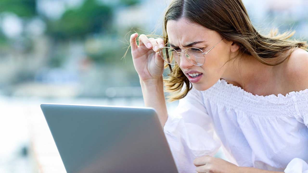 junge Frau blickt verwundert und verwirrt auf einen Laptop