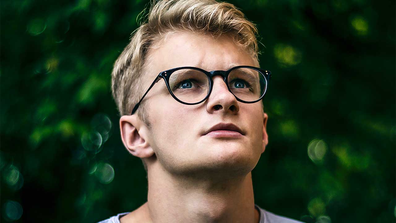 junger Mann mit Brille blickt leicht nach oben